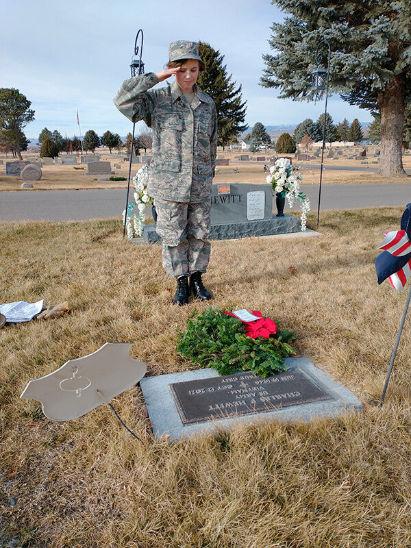 Cadet Fae McNair of Powell salutes after placing a wreath on former Civil Air Patrol Chaplain Charles Hewitt&rsquo;s gravesite at Crown Hill Cemetery.
