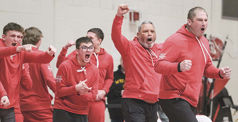 Orrin Jackson, Kaiden Rubash and the Trapper wrestlers celebrate alongside coaches Jim Zeigler and Chris Cooley after Cody Pinkerton won via pin to win the match against No. 1-ranked Western Wyoming on Saturday.