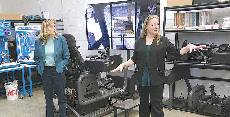 Northwest College President Lisa Watson (left) watches as CTD administrator Christi Greaham tells assembled board of trustees and staff about the new simulators available at the armory.