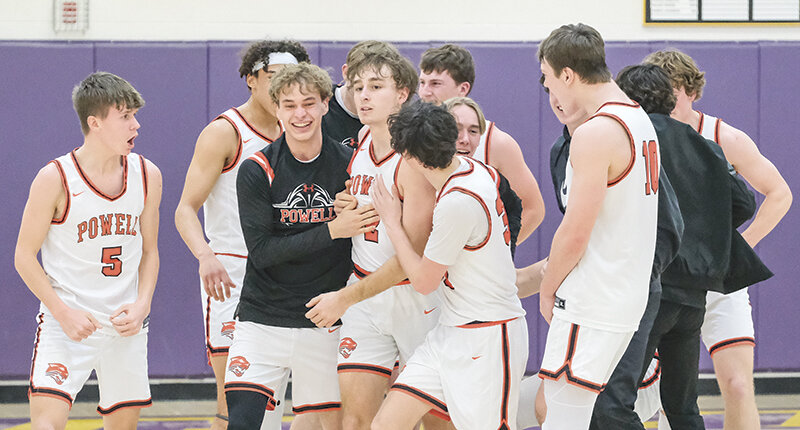The Powell Panther boys basketball team swarms Marshall Lewis (2) after he hit a buzzer-beater to defeat Lovell 54-52 in the 3A West Regional title game Saturday night.