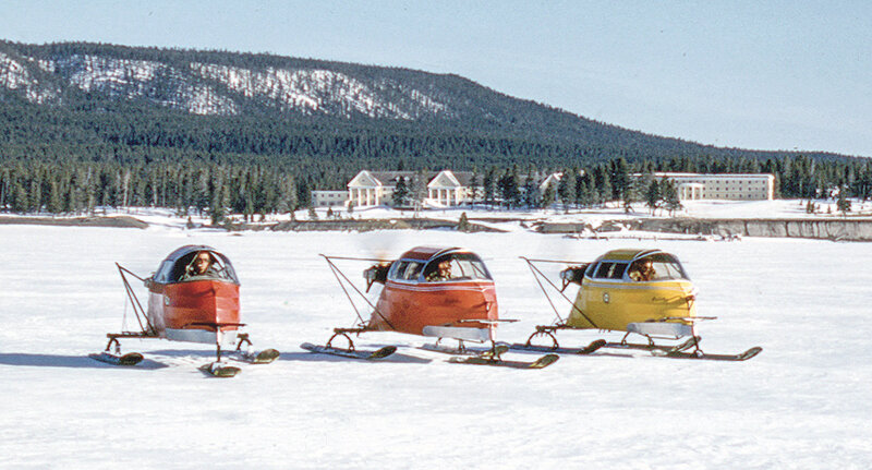 Three snowplanes on the ice of Yellowstone Lake with Lake Hotel in the background, 1955.