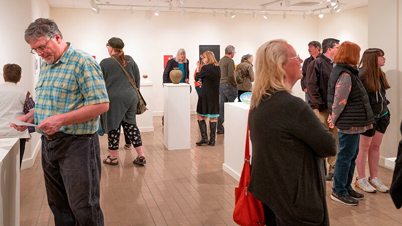 People check out the artwork on display at a previous Juried Student Art & Design Exhibit in the Northwest Gallery in the Cabre Building.