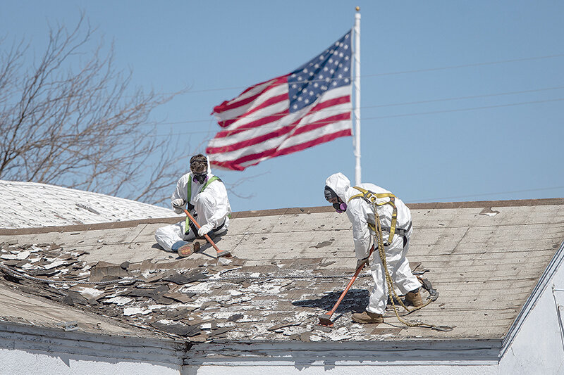 Chris Grondin and Jose Garcia work to remove asbestos shingles from the roof of the former VFW lodge in Powell. The property was purchased by the senior center, which plans to demolish the building and build a new senior center.