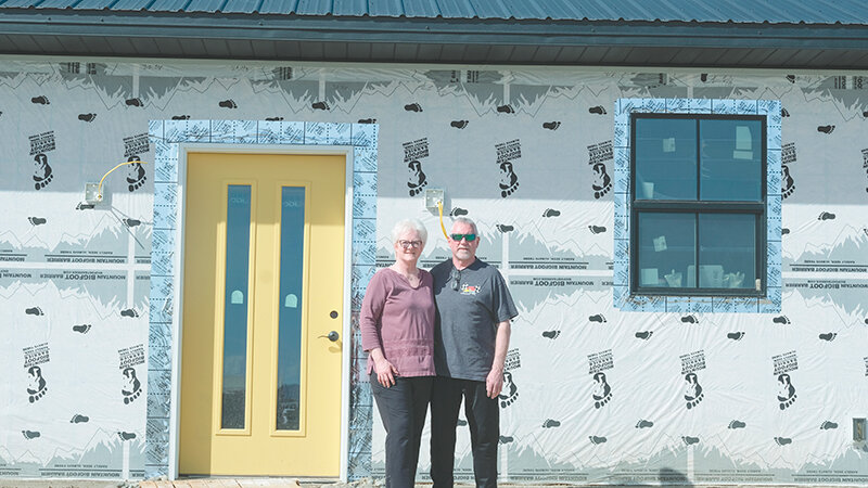 Tim and LeAnne Kindred stand in front of their new home which is under construction. The home will be a shop house with ample room both for Tim&rsquo;s business and for storage and hobbies.