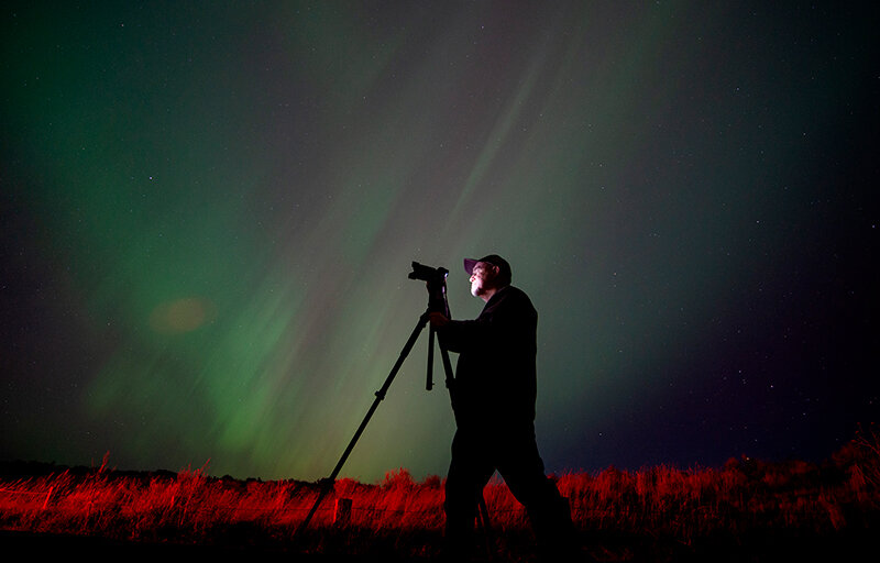 Night Skies photographer Greg Wise takes in the aurora borealis Friday night at Deaver Reservoir. A foot on the brakes from a nearby car lights up the ground, but the sky is all natural during the northern lights event.