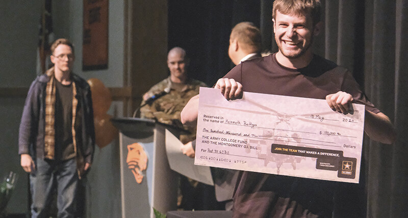Kenneth Bettger (right) shows off his check during the Senior Recognition Ceremony on Monday night. Bettger has enlisted in the U.S. Army and is a recipient of the Post 9/11 GI Bill valued at $100,000. This year&rsquo;s graduating class was offered over $8 million in scholarships.