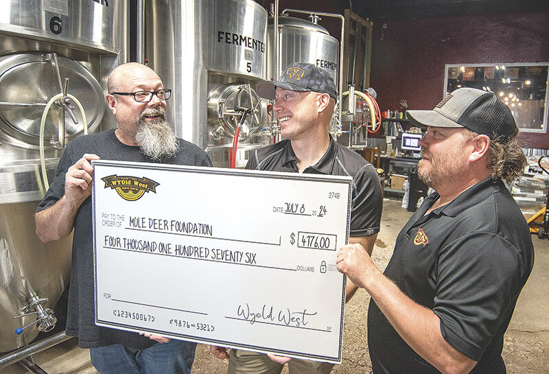 Head brewer Steve Samuelson (left) and Assistant brewer Zac &lsquo;Spud&rsquo; Baker (right) present Wyoming Regional Director for the Mule Deer Foundation Shawn Blajszczak a giant check from the first six months of profits from the sale of the charity collaboration beer, Mule Deer Beer.
