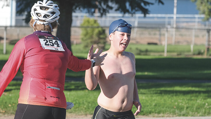 Jake Williams races to tag his mom Bridget&rsquo;s hand before sending her out on the biking portion of the Sugar Beet Classic triathlon on Aug. 24 in Powell.