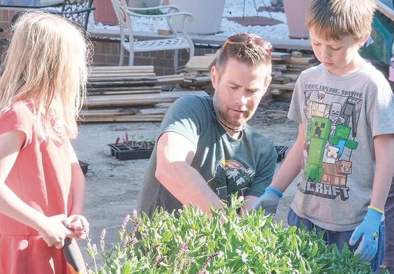 Westside Elementary School PE teacher Luke Robertson (left) helps students at the Powell Valley Care Center in late May where the school and community members worked to plant a garden. The garden will be managed by care center staff and residents in the summer.