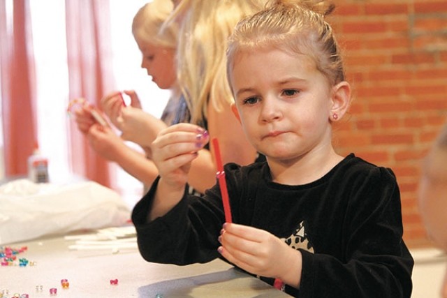 Three-year-old Campbell Foulger of Powell concentrates as she puts a bead on a pipe cleaner to make a candy cane decoration during Santa’s Workshop Friday at The Commons.