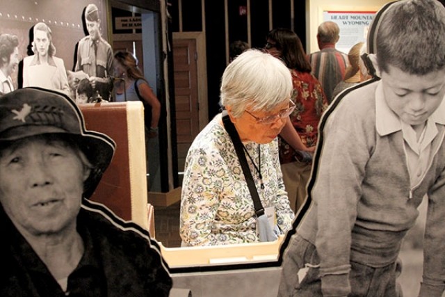 Shizuiko Morita of Virginia, a former internee at the Heart Mountain Relocation Center, is framed by historical, life-sized photos of internees while she reads information on another display at the new Heart Mountain Interpretive Learning Center. The center will be open daily from 10 a.m. to 5 p.m. through September.