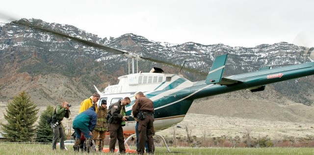Park County Sheriff’s deputies Chad McKinney (right) and J.J. Schwindt visit with pilot Josh Hellyer (not visible) while three members of a wilderness rescue team prepare to board the helicopter to provide medical treatment for an Idaho couple after their plane crashed a few miles beyond the head of the South Fork of the Shoshone.