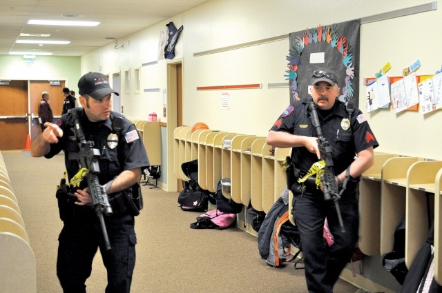 Powell Police Officer Paul Sapp (left) gestures to Sgt. Roy Eckerdt as they work to ‘clear’ a wing of Southside Elementary School during a Monday drill conducted by Park County School District No. 1. Officers ultimately located the armed and destraught parent (a role player) in a classroom and took him into custody.