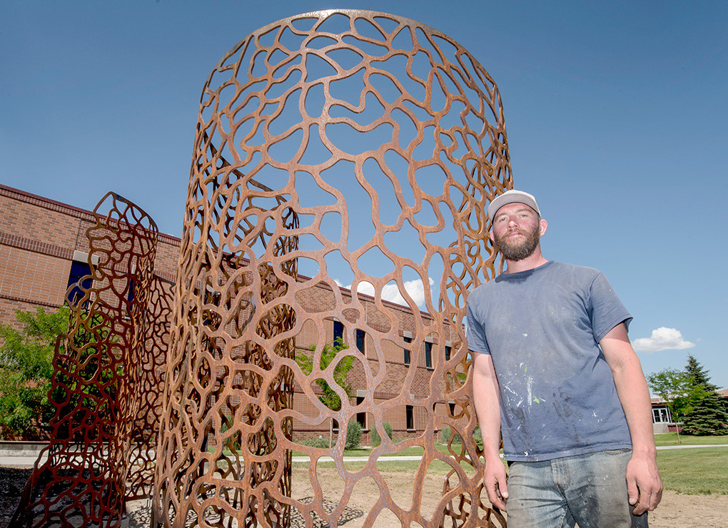 Artist Jodie Roth Cooper poses with his sculpture, ‘Infinite Pattern S’s’ after a long day of installing the new piece on the east side of Northwest College’s Yellowstone Building.