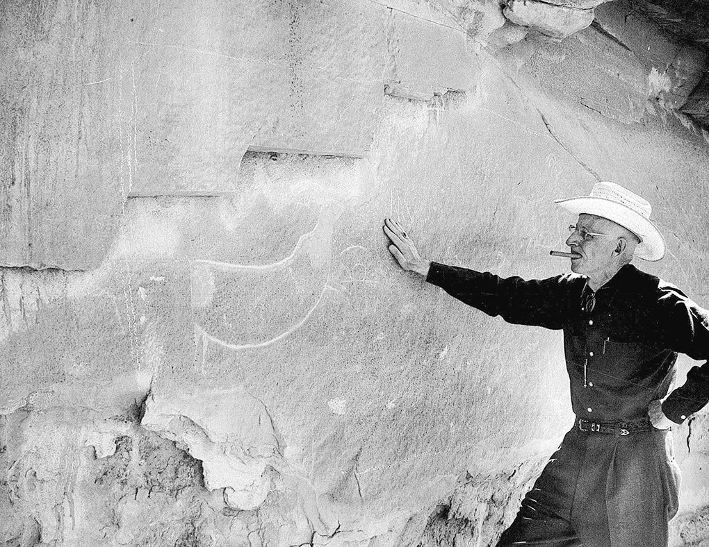 Harold McCracken, former director of the Buffalo Bill Center of the West, inspects Plains Indian rock art prior to purchasing it and having it removed from a cliff in 1962 for display at the museum.
