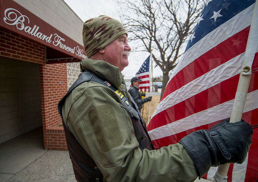 Sully Sullivan, of the Patriot Guard Riders, stands post with the American flag in hand outside Ballard Funeral Home in Cody Friday.