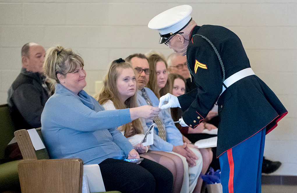 Shelley Statler, granddaughter of Joseph J. Mulvaney, is presented with a memorial pin by  Honor Guard member Bill Buntyn while the Statler family, including (from left) Kaylee, 17, Ron, Jenna, 13, Brittany, 15, and Deacon Rick Moser, watch from the front row.