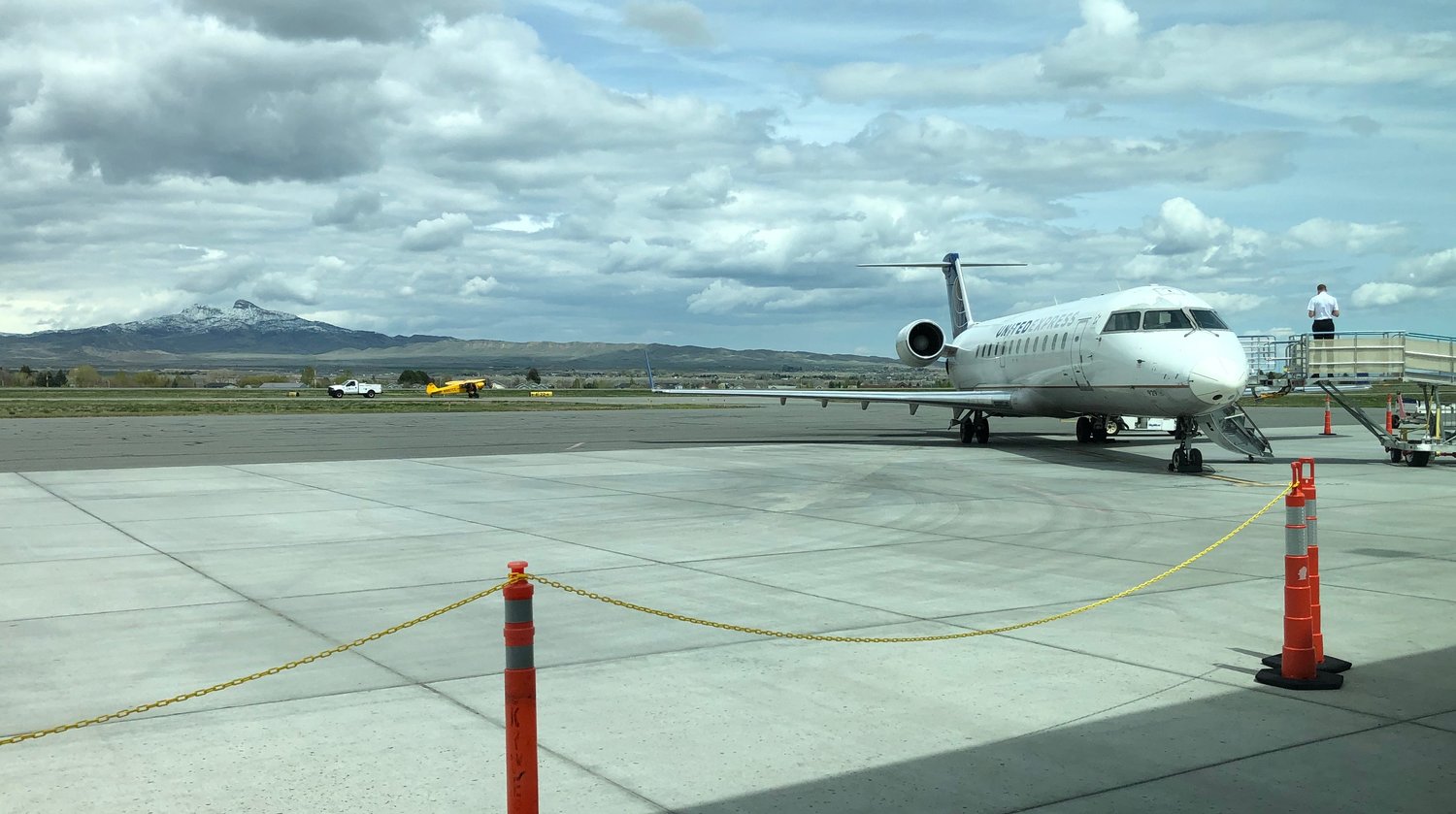 While a pilot from a delayed United flight watches, a private plane is moved along the runway after crashing at Yellowstone Regional Airport Saturday morning.