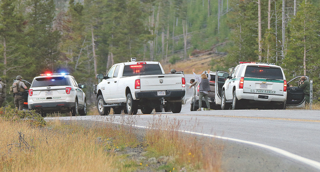 Law enforcement officers at Yellowstone National Park detain two suspects near Sedge Bay while searching for two fugitives. The truck was stopped after a tip, but the occupants were not the fugitives sought and were soon back on their way through the park.