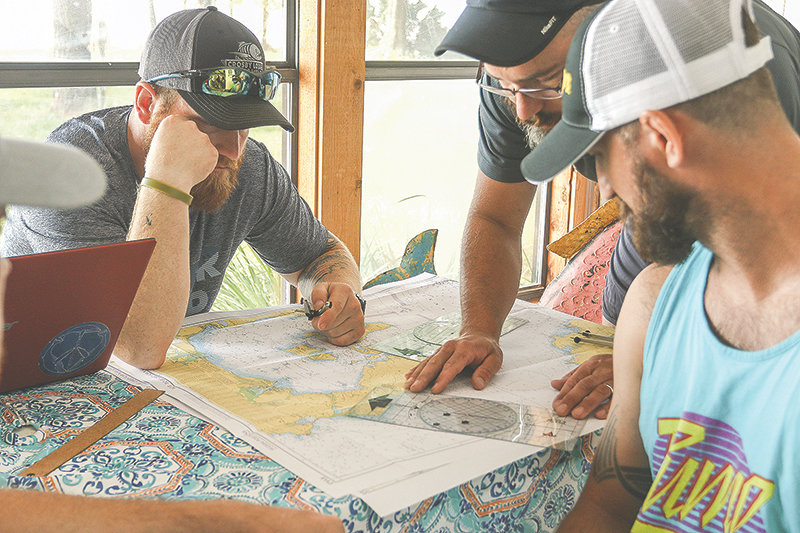 Carl Christensen (Navy), Luke Holton (Army), John Fannin and Evan Stratton (Marines), check maps for their trans-Atlantic trip in a row boat.