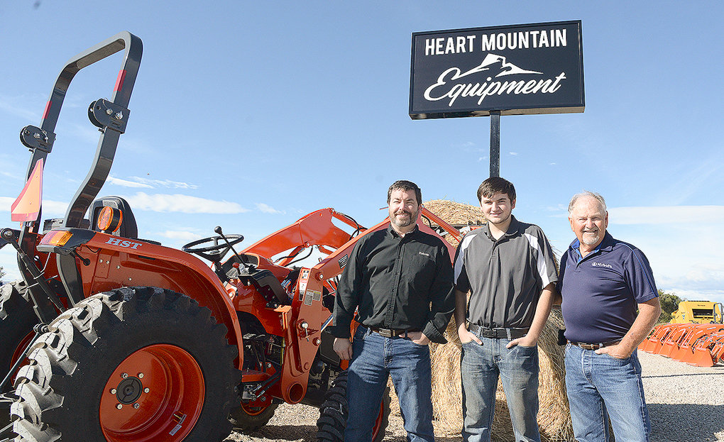 Three generations of Heart Mountain Equipment dealers — Greg WIlson, Holden Wilson and Terry Swenson — stand before the sign featuring the business’s new name.