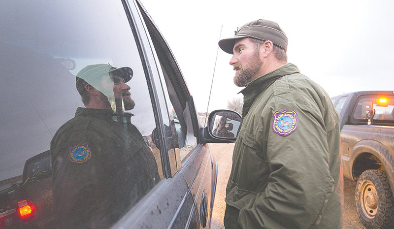 Corey Class, Cody Region wildlife management coordinator for the Wyoming Game and Fish Department, talks with unsuccessful hunters while manning a check station east of Lovell Monday night. The department is asking hunters to submit samples of their deer to be tested for chronic wasting disease.