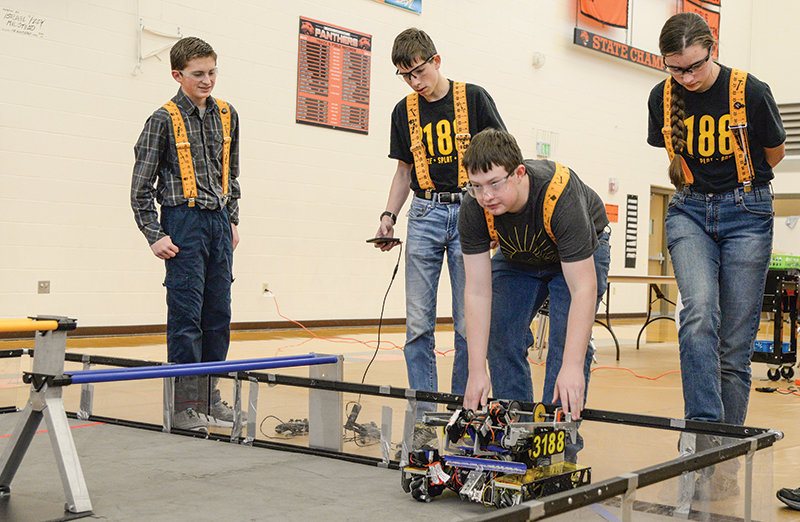 Owen Fink, Daniel Merritt, Cade Sherman, and Jenna Merritt, members of team Squiggle Splat Bang, try out a robot on a test field prior to the competition at the Robo Rumble on Jan. 11.