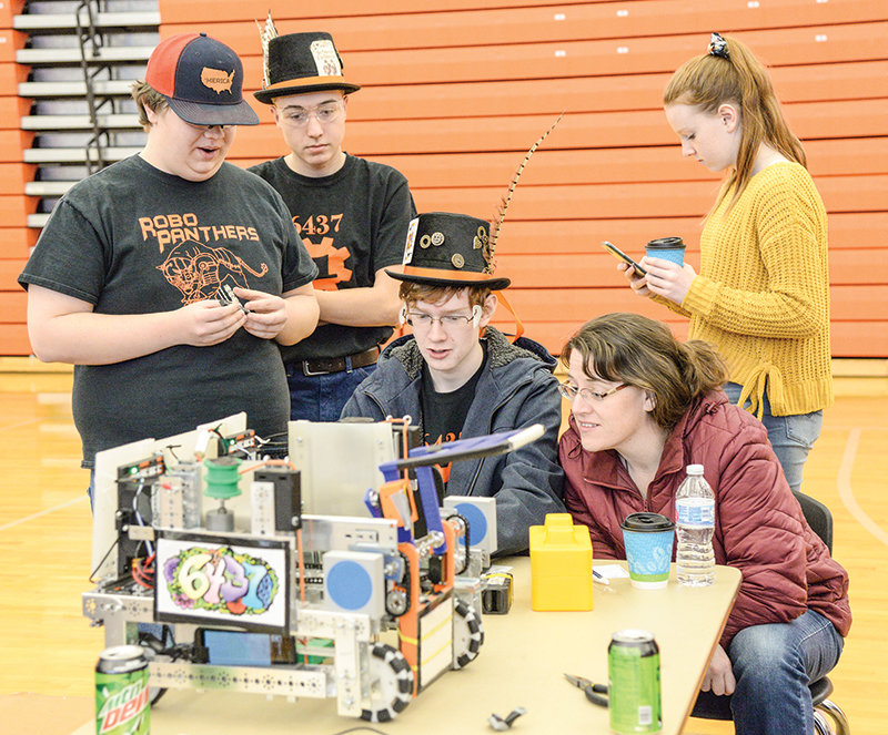 Nate Belmont of the Robo Panthers, works with Ethan Petrie and Gus Miller on the Mad Hatter team’s robot, while Gus’s mom Julie Miller looks on. Pictured in the background is Kate Miller.