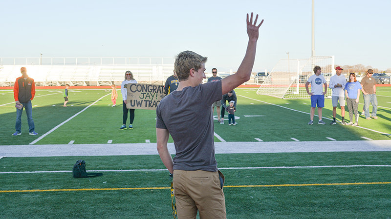 From a safe distance, Jay Cox waves to a group of people who came out to support him on Tuesday night at Panther Stadium, as he signed to join the University of Wyoming track team next school year.