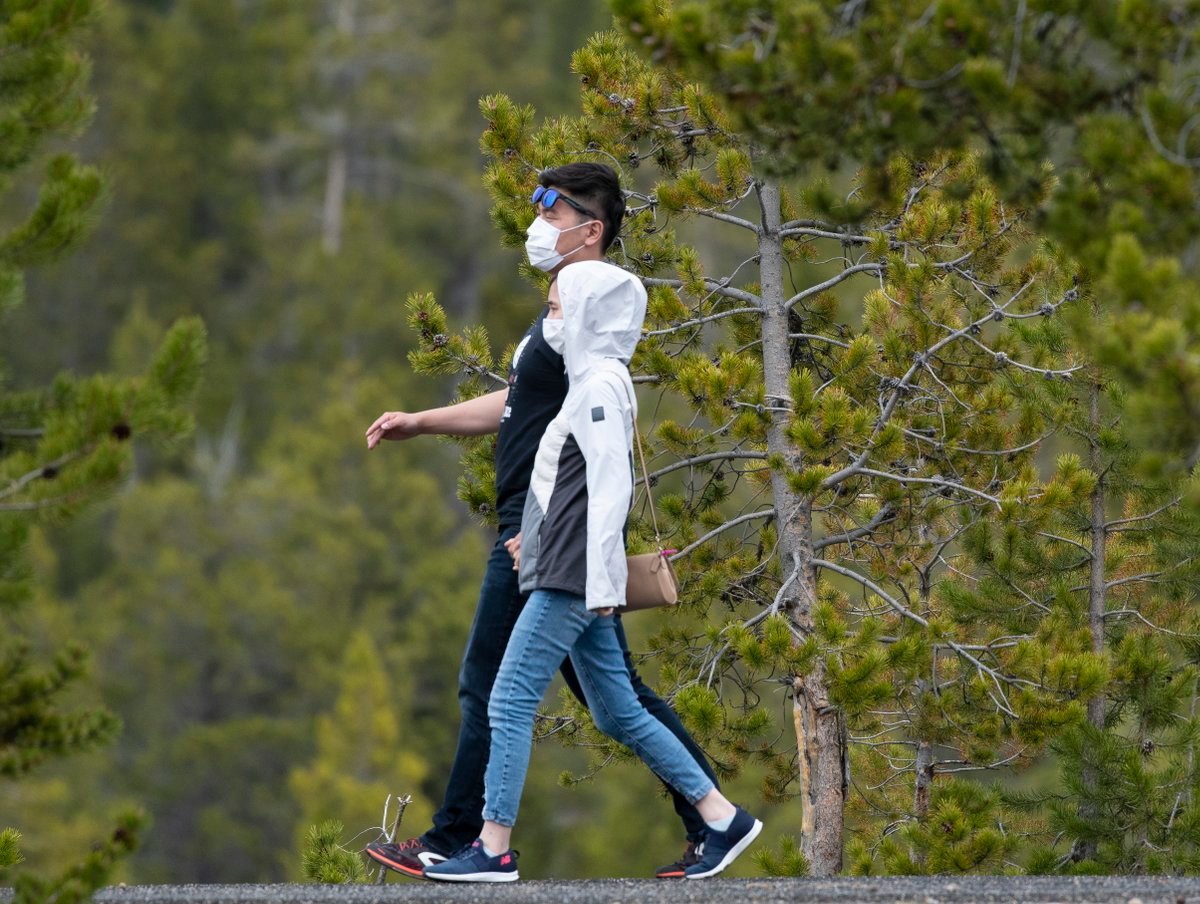 A pair of visitors to Yellowstone National Park stroll down a trail during the opening day of the park's summer season, on May 18. An increasing number of tourists in the area will 'complicate' the way that local health officials deal with the COVID-19 pandemic.