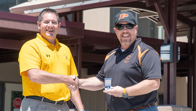 Powell High School tennis coach Joe Asay (at right) receives his award for boys’ tennis coach of the year from Wyoming Coaches Association Past President Mike Lashley. Under Asay’s leadership, Powell won its first-ever boys’ tennis title in 2019. Asay was set to receive the award at a banquet this month, but Lashley hand-delivered it after the event was canceled.