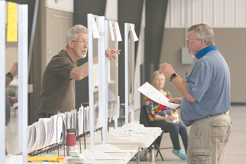 Election official Howard Haun (left) directs Nevin Jacobs to the next station at the Park County Fairgrounds after he received his ballot for Tuesday’s primary election. The county consolidated polling places to four locations in Cody, Powell and Meeteetse.