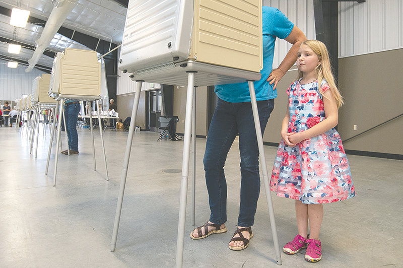 Liza Smith, 8, watches as Barbara Smith votes in Tuesday’s primary election. It was the second time Liza has been able to watch the process — this time enjoying a lollipop during the fun.