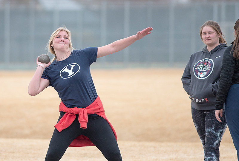 Whitney Hull pushes a shot Tuesday at throwing practice while Cassidy Miner looks on. Roughly 100 student-athletes turned out for the track-and-field team’s first practice.