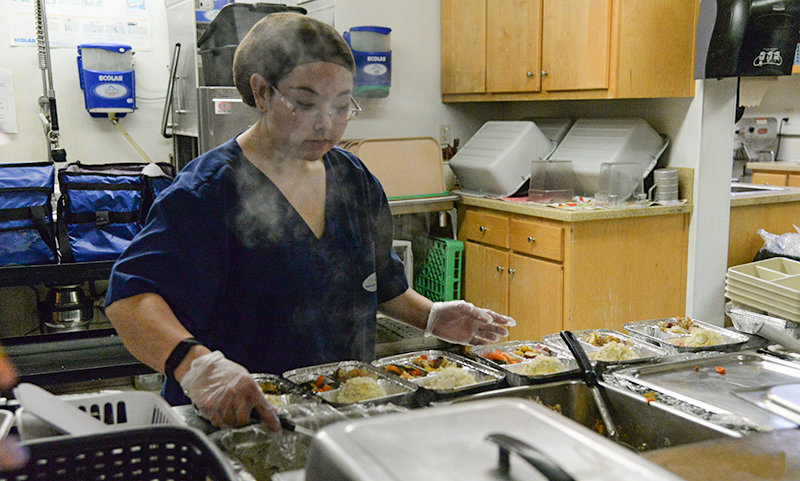 Steam rises off lunches last week as Kari Kawano packs delivery meals for seniors. Under the leadership of Kitchen Supervisor Mandy Anderson, a crew of four kitchen staff at the Powell Senior Center prepared over 34,000 meals this past year.
