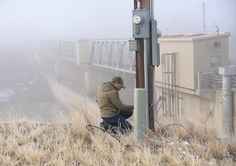Jason Burckhardt, Wyoming Game and Fish Department fisheries biologist, does some work at a utility pole by Willwood Dam at the start of the operation on a foggy Wednesday morning.