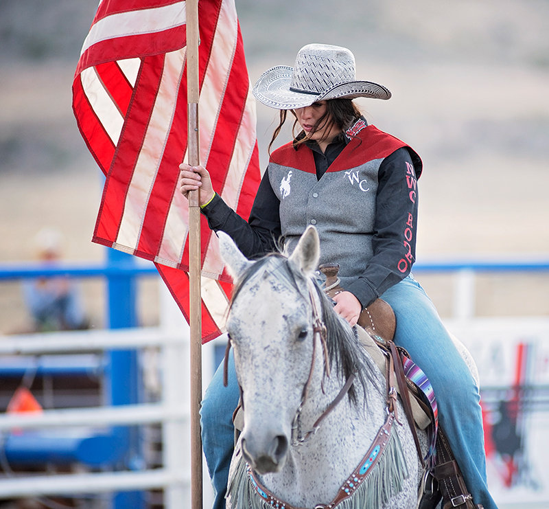 Northwest College cowgirl Dusty Miller of Cowley holds the flag during the opening ceremony of the Trapper Stampede in September. The fall event kicked off the college rodeo season.