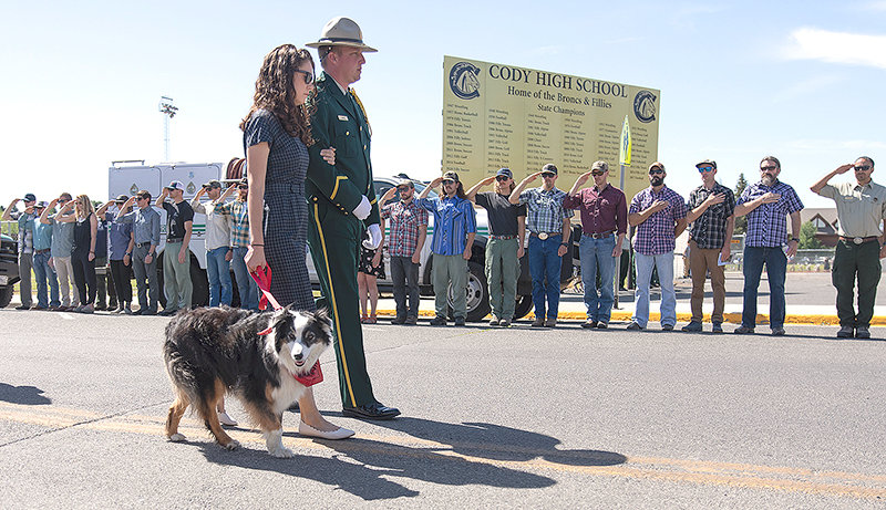 Michelle Hart, the wife of fallen smokejumper Tim Hart, holds the couple’s dog, Dash, while being escorted through a Cordon of Honor by the U.S. Forest Service Honor Guard Saturday morning in Cody. Firefighters lined Beck Avenue and stood at attention as Hart’s body was brought to Spike Vannoy Field for the memorial service.