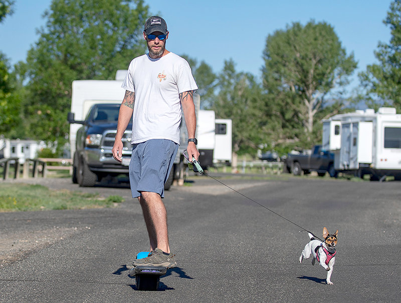 Josh Cannon, of Rincon, Georgia, rides a One Wheel electric skateboard while walking his rat terrier, Piper, while camping at Buffalo Bill State Park. Despite making reservations in early spring, the campers couldn’t get the site they wanted for their visit to Wyoming.
