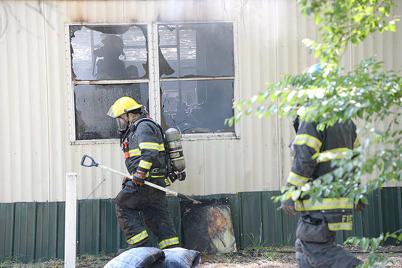 Members of the Powell Volunteer Fire Department work to extinguish a fire that broke out in Scott’s Granite Park midday Saturday. The trailer was a total loss.