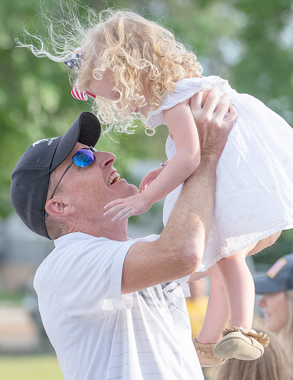 NFL football coach John Fassel lifts his daughter, Anna, into the air.