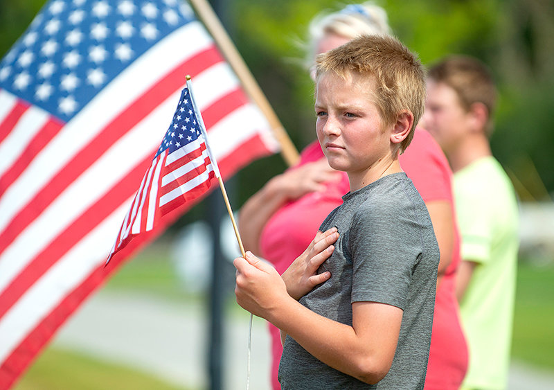 Cache Thompson places his hand on his heart as the remains of Alva R. Krogman pass through downtown Cowley Monday. From Billings to Worland, residents came out to pay their respects to the Vietnam veteran, who died in 1967.