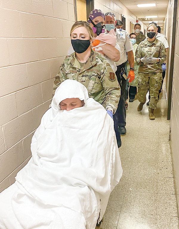 Wyoming Air National Guard Administrative Specialist Senior Master Sgt. Jennifer Ballenger helps transport a guest of Operation Allies Refuge after assisting the woman with an emergency delivery of her baby.