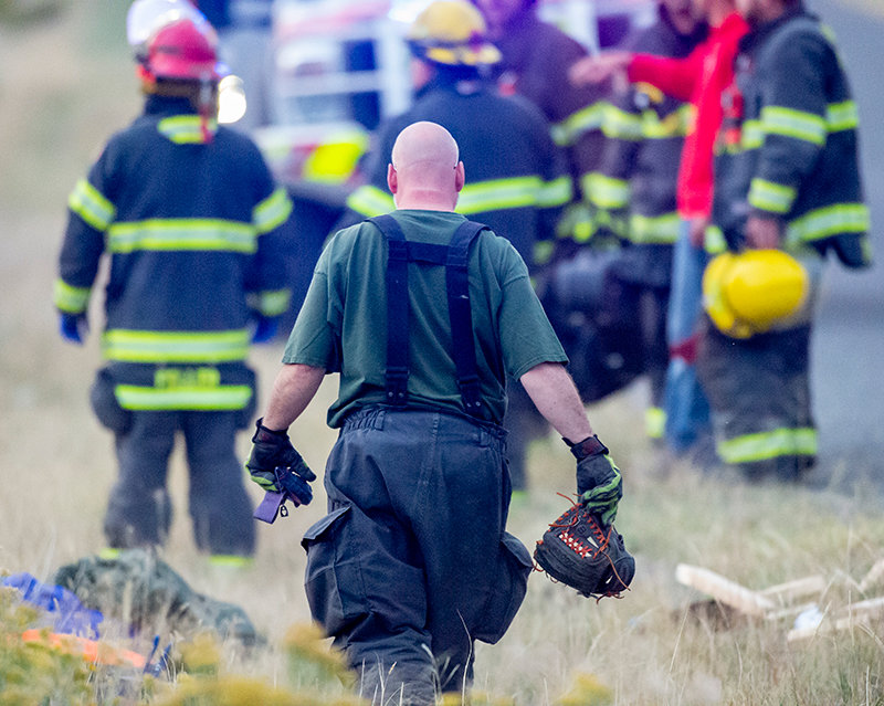 Powell firefighter Jim Dobbs carries a baseball glove that was tossed from a truck that crashed Sunday evening outside Ralston. The driver of the vehicle remained hospitalized in Billings on Wednesday.