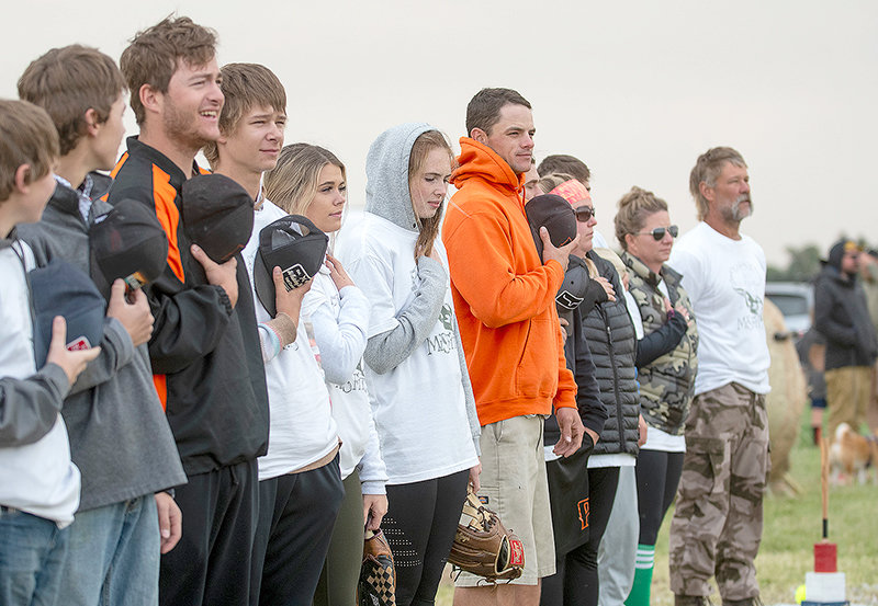 Tyler England (in the orange hoody) sings the National Anthem with players on the Misfits softball team. England has served as the assistant coach of Powell’s American Legion baseball team, the Pioneers, and played professional baseball in California.