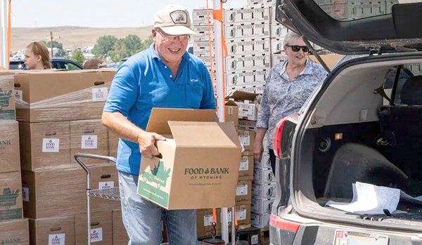 A volunteer at the Moorcroft Interfaith Community mobile pantry loads boxes into the car of a client. On its busiest day, the pantry served over 350 families.