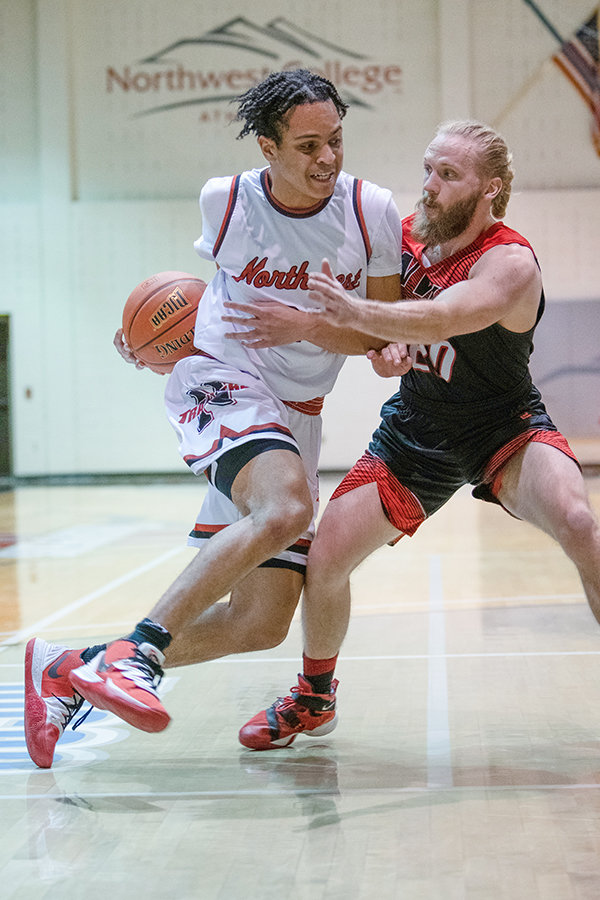 NWC freshman Bryson Stephens drives against former Trapper Levi Peterson during a game against the Northwest Alumni All-Stars. Stephens finished with a career high 34 points, as the Trappers routed the all-star team on Friday and Saturday.