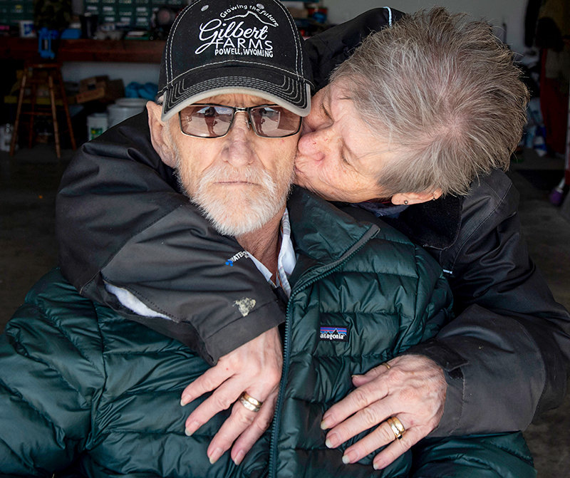 Dawn Gilbert plants a kiss on her husband’s cheek while enjoying a break outdoors earlier this month. Dwight Gilbert is battling cancer and has been confined inside the family home.