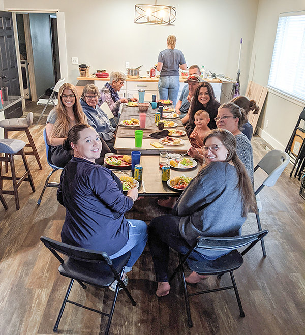 The Siggins family enjoys a meal in their new home. Starting at the top left side of the table Teddy Lindberg, Lauren Tophoj, Cianna Siggins, Stormi Siggins, Cori Siggins, Lisa Siggins, Charity Siggins holding Weston Siggins, Callie Lundvall, Easton Siggins (hidden), Colby Siggins and Cassidy Siggins.