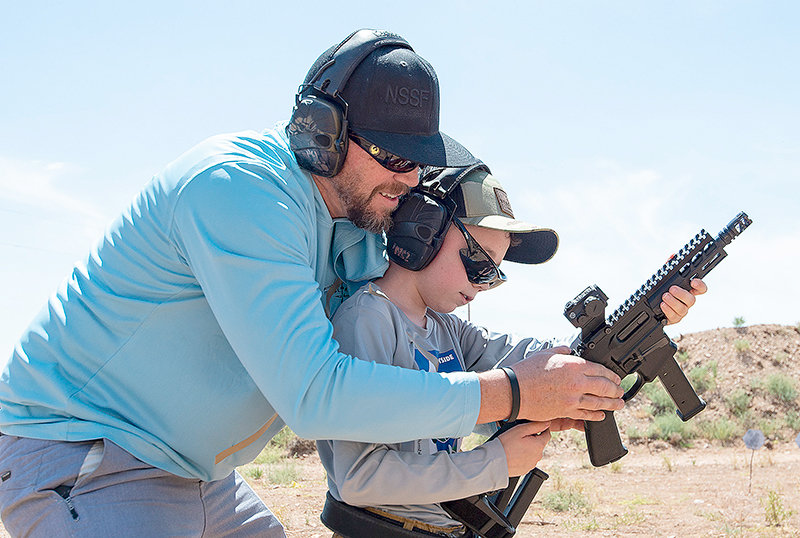 Nephi Cole helps his son Griffin prepare for the fourth stage at the Surefire World Multi-gun Championships Saturday in Cody. At 12, he was the youngest competitor at the match and competed in the recreational division.